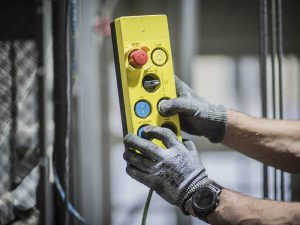 Kuvituskuva, jossa henkilö pitelee hissin ohjausyksikköä kädessään. A-kassa Avoin työttömyyskassa