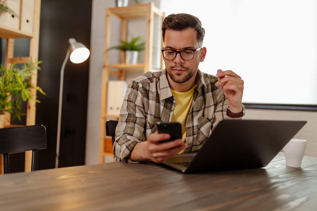 Kuvituskuva, jossa mieshenkilö katsoo puhelimelta jotain asiaa mietteliäänä.