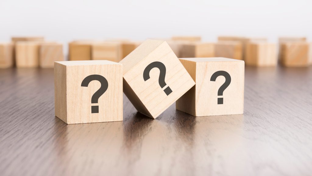 Kuvituskuva, jossa puisia noppia, joissa kysymysmerkkien kuvia.