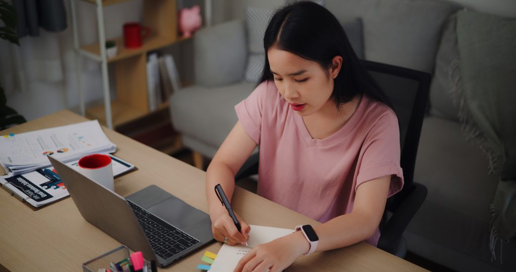 Henkilö tekee merkintöjä mustikirjaan