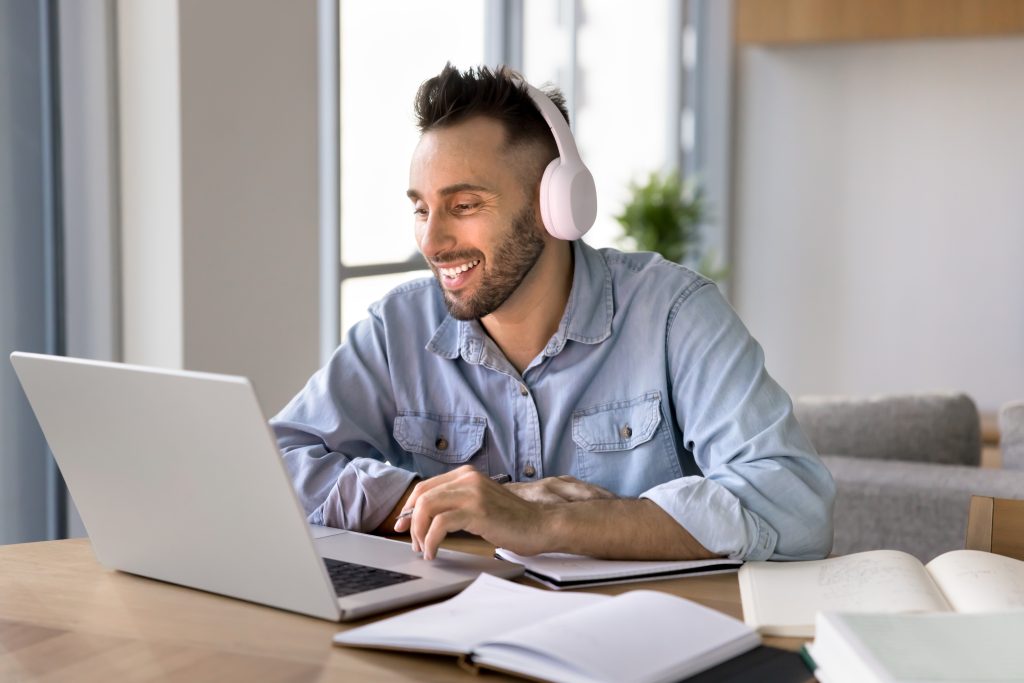 kuvituskuva, jossa henkilö katselee tietokonetta kuulokkeet päässä