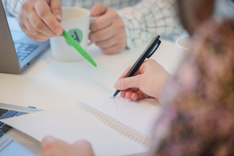 kaksi henkilöä muistivihon ääressä