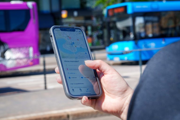 Henkilö katsoo puhelimella bussiaikatauluja