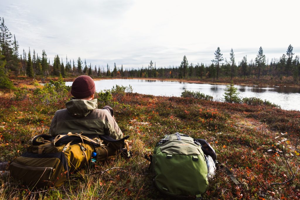Henkilö on vaeltamassa syksyisessä maastossa.